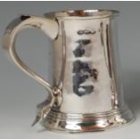 An early George III silver tankard, having double monogrammed S scroll handle and on stepped flaring