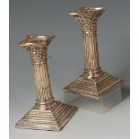 A pair of Edwardian silver Corinthian column candlesticks, having beaded detachable sconces,