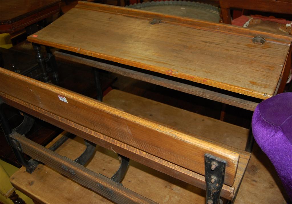 An early 20th century elm and black painted wrought metal child's double school desk with integral