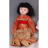 An early 20th century European composition doll of a Japanese baby, having fixed brown eyes, painted