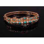 A Victorian style yellow metal seed pearl and turquoise hinged bangle, with safety chain,