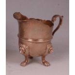 A George V silver cream jug, of helmet form, raised on three lion mask paw feet, 7.