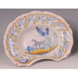 A 19th century French faience barbers bowl, underglaze decorated in shades of blue, green and ochre,