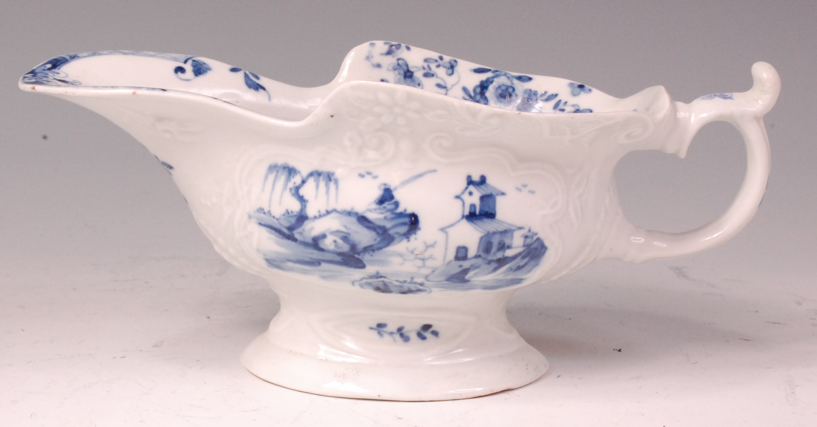 An early Worcester porcelain sauceboat, relief moulded and underglaze blue decorated with