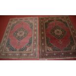 A pair of Persian woollen Tabriz style rugs, the red ground with a central lozenge medallion