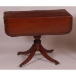 A Regency mahogany and rosewood crossbanded pedestal Pembroke table, raised on four outswept