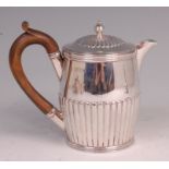 A late Victorian silver hot water pot, of half-reeded barrel shape, having finial topped dome cover,