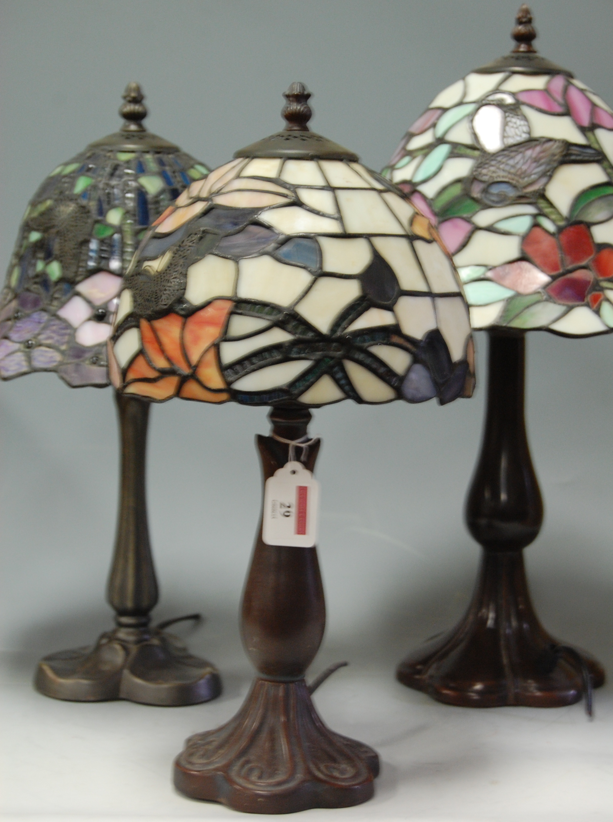Four various Tiffany style bronzed metal table lamps, each with coloured glass shades  Condition