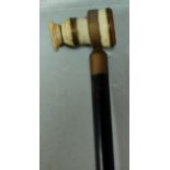 A circa 1900 walking stick having an ebony shaft and ivory monocular handle