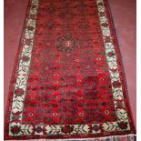 A semi-antique Persian woollen rug, having a red complex field within continuous trailing border,