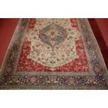 A Persian woollen Tabriz carpet, having a central lozenge medallion issuing scroll flowers and