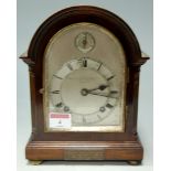 A 1920s mahogany cased mantel clock, the arched silvered dial with Arabic numerals, signed '