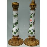 A pair of Victorian pedestal lamp bases, each having a glass stem painted with leaves and berries,