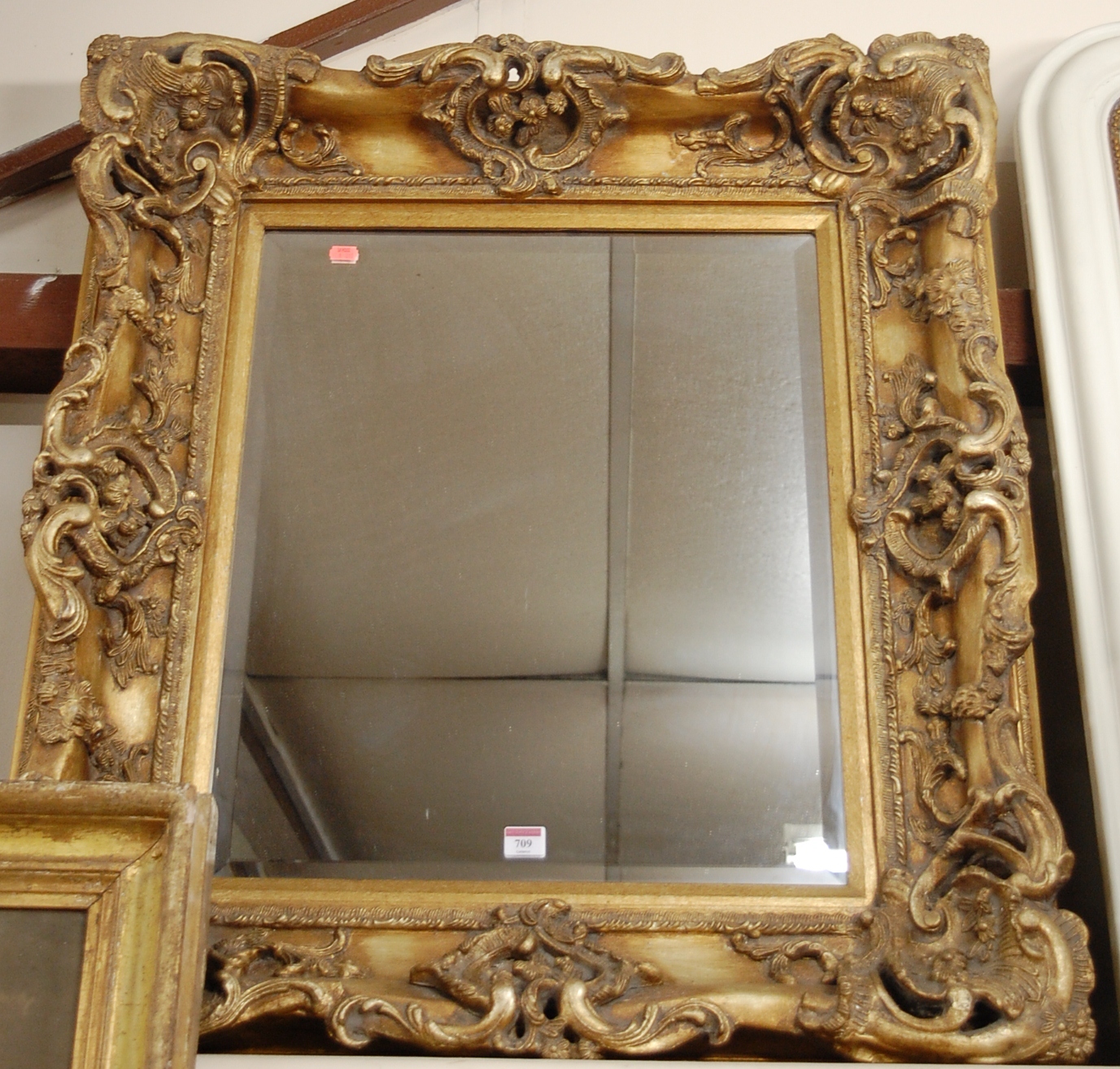 A reproduction gilt composition framed and bevelled wall mirror in the Rococo style