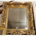 A reproduction gilt composition framed and bevelled wall mirror in the Rococo style