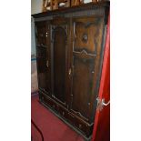 An early 20th century moulded oak double wardrobe enclosed by panelled doors with drawers below