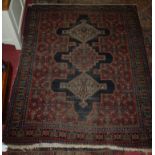 A Persian woollen floral geometric stylised rug (worn), together with one other smaller similar