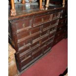 An antique joined oak chest having an arrangement of various multiple drawers