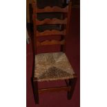 A set of four oak ladder back dining chairs with rush seats on square cut supports