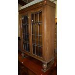 A 1930s moulded oak lead glazed double door bookcase