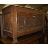 A circa 1900 heavily carved oak hinged top coffer,