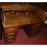 An early 20th century oak roll top kneehole writing desk