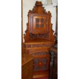 An Edwardian walnut freestanding corner cupboard having low relief floral carved detail