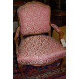 A Louis XV style carved walnut framed and red floral upholstered fauteuil