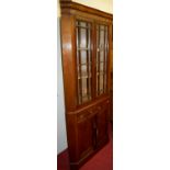 A mahogany freestanding four door corner cupboard having twin glazed door upper section