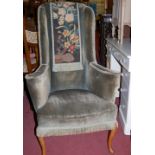 An early 20th century walnut framed and part-floral tapestry upholstered wingback armchair