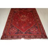 A Persian woollen Shiraz rug, the rust coloured field with diamond lozenge medallion,