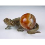 A Victorian novelty brass paperweight, naturalistically modelled as a lizard with an agate sphere, 8