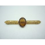 An early 20th Century 18ct gold and citrine bar brooch, the crown set stone being held above a