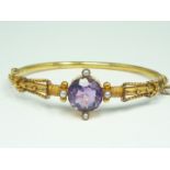A Victorian Etruscan Revival 9ct rose gold, amethyst and pearl bangle, the cannetille decorated face