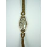 An early 20th Century lady's 18K gold wristlet watch, having silvered face in elongated tonneau