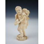 A Meiji Japanese small ivory okimono modelled as a figure carrying a rabbit in his hands and a