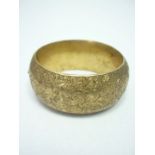 A late 19th / early 20th Century silver gilt bangle, of hollow D section, the face densely