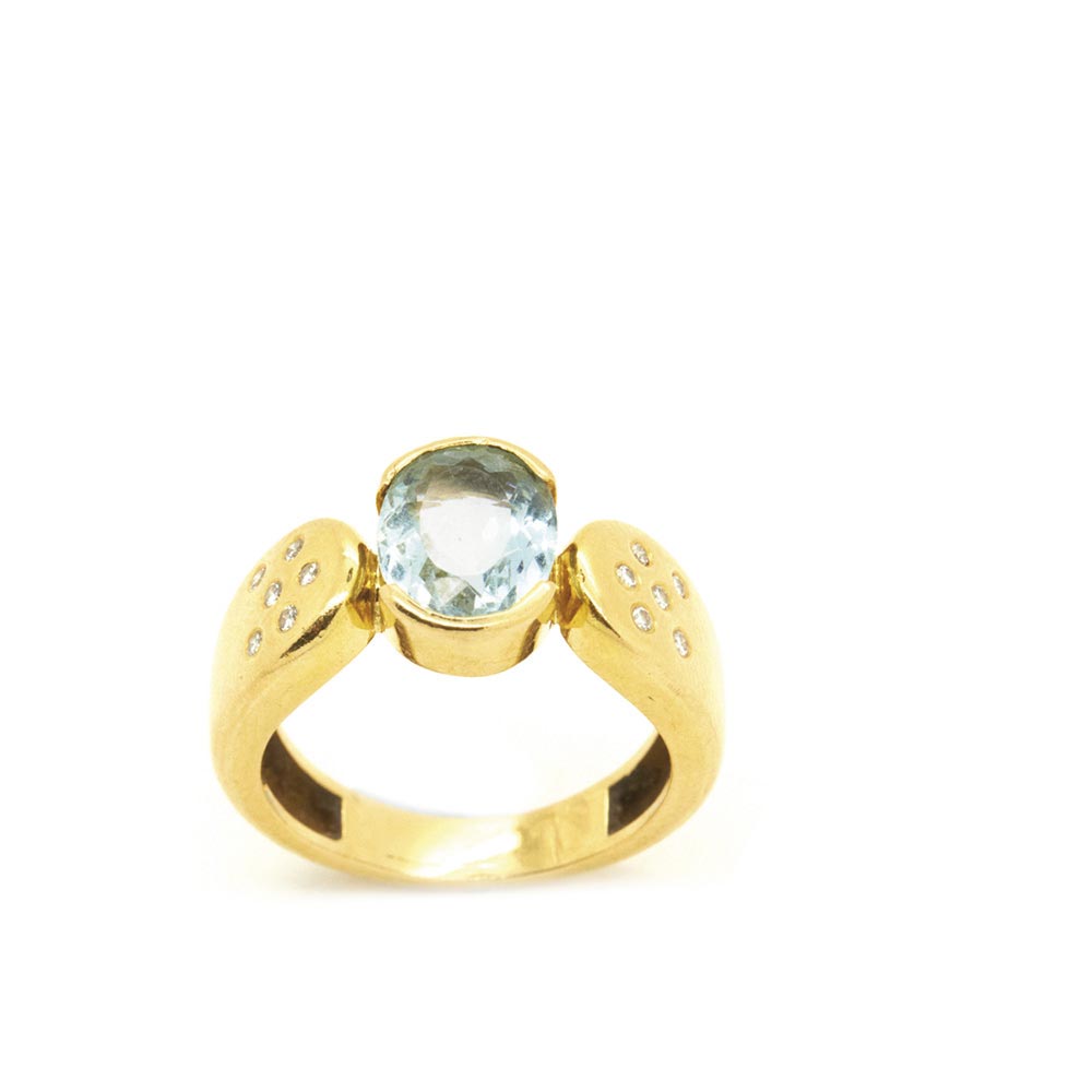 Gold, blue topaz and diamonds ring Sortija en oro con topacio azul talla oval flanqueado por