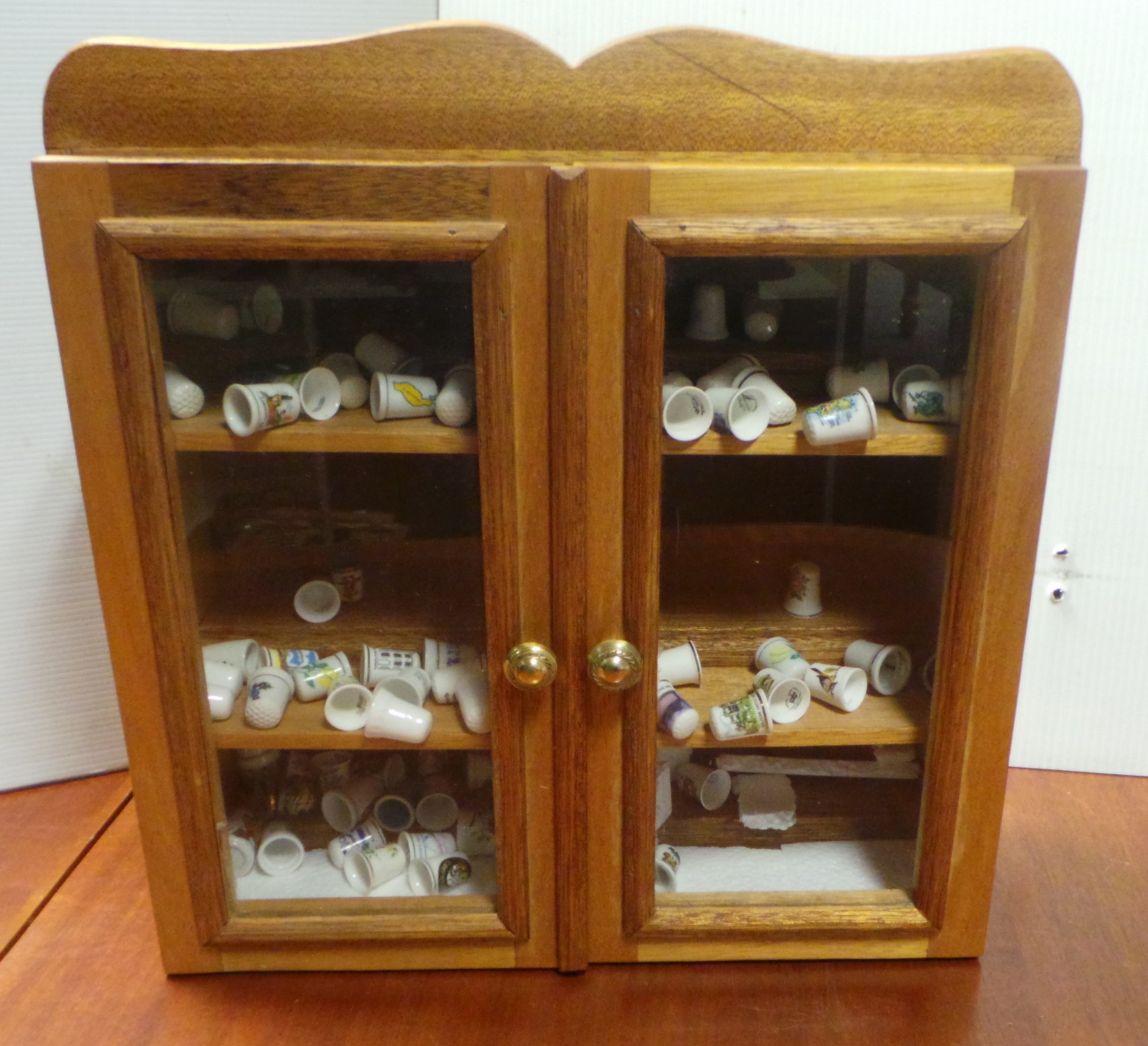 Miniature 2 door pine wall cabinet and large quantity of porcelain thimbles