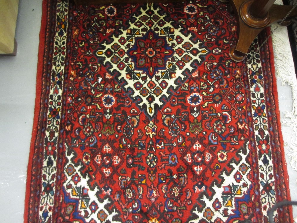 20th Century Hamadan rug with medallion and all-over Herati design on a red ground with borders,