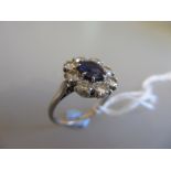 Single stone sapphire and eight stone diamond set oval cluster ring on a white metal mount,
