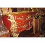 Continental reproduction gilt and red painted two drawer commode with applied carved decoration,