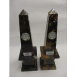 Pair of composite marble obelisks inset with modern clocks