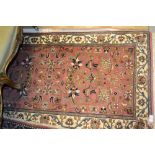 Small Indo Persian rug with stylised floral design on a pink ground