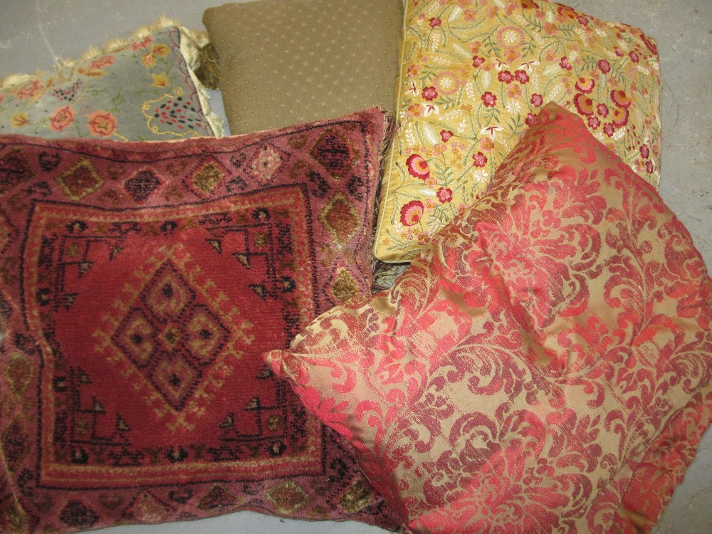 Two embroidered cushions and three other cushions