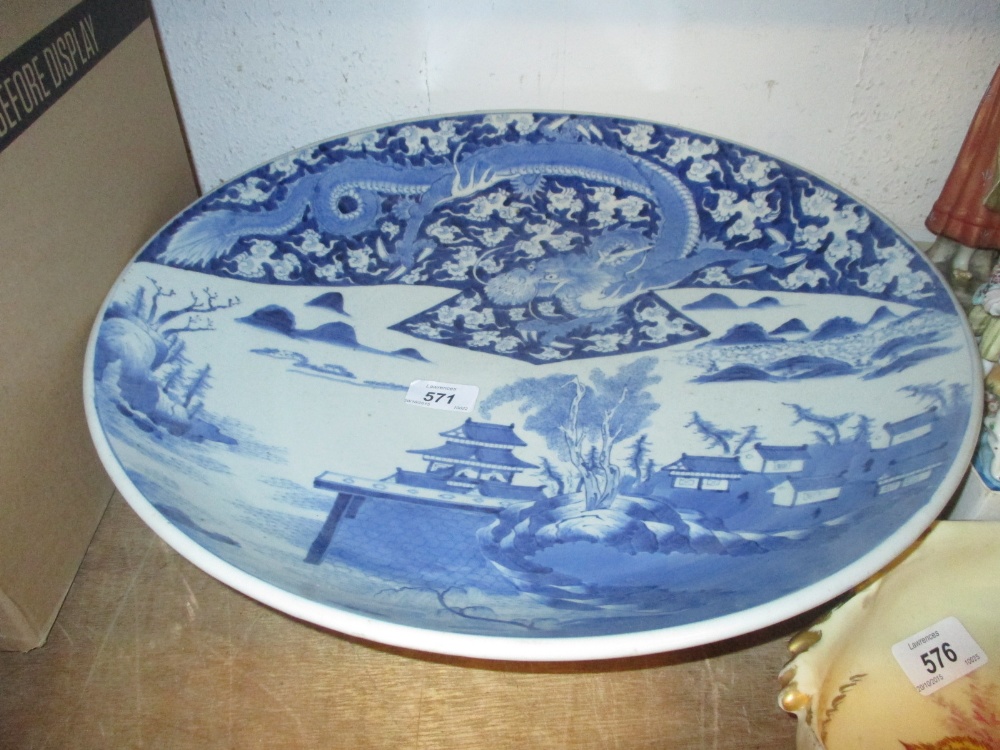 Large Chinese blue and white shallow bowl decorated with a dragon and buildings in a landscape