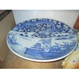 Large Chinese blue and white shallow bowl decorated with a dragon and buildings in a landscape