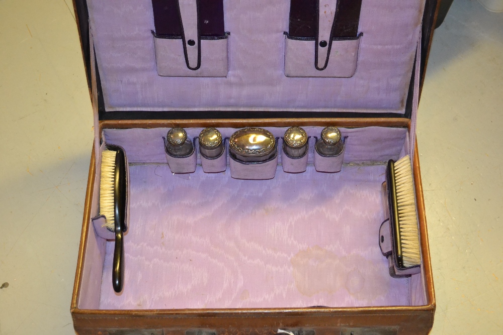 Leather dressing case with fitted interior including five silver mounted cut glass bottles
