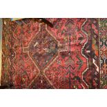 Shiraz rug of medallion and floral design with multiple borders on a wine ground,