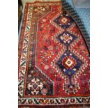 Shiraz rug having central hooked medallions and multiple borders on a red ground
